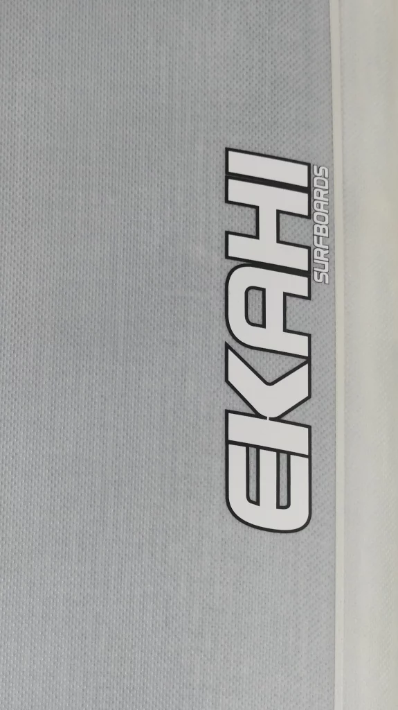 Close-up of the Ekahi logo on a grey Long Ekahi carbon surfboard