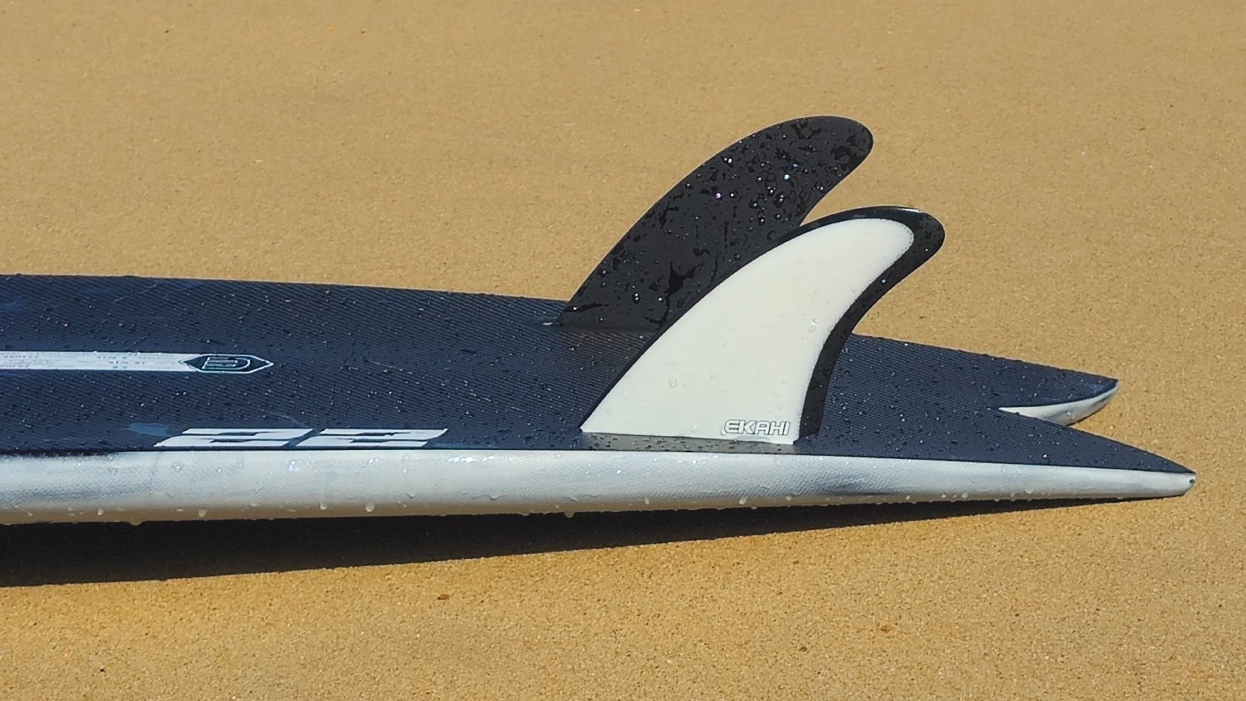 View of the Ekahi twin fins on the twin fish 22 pearl white carbon surfboard