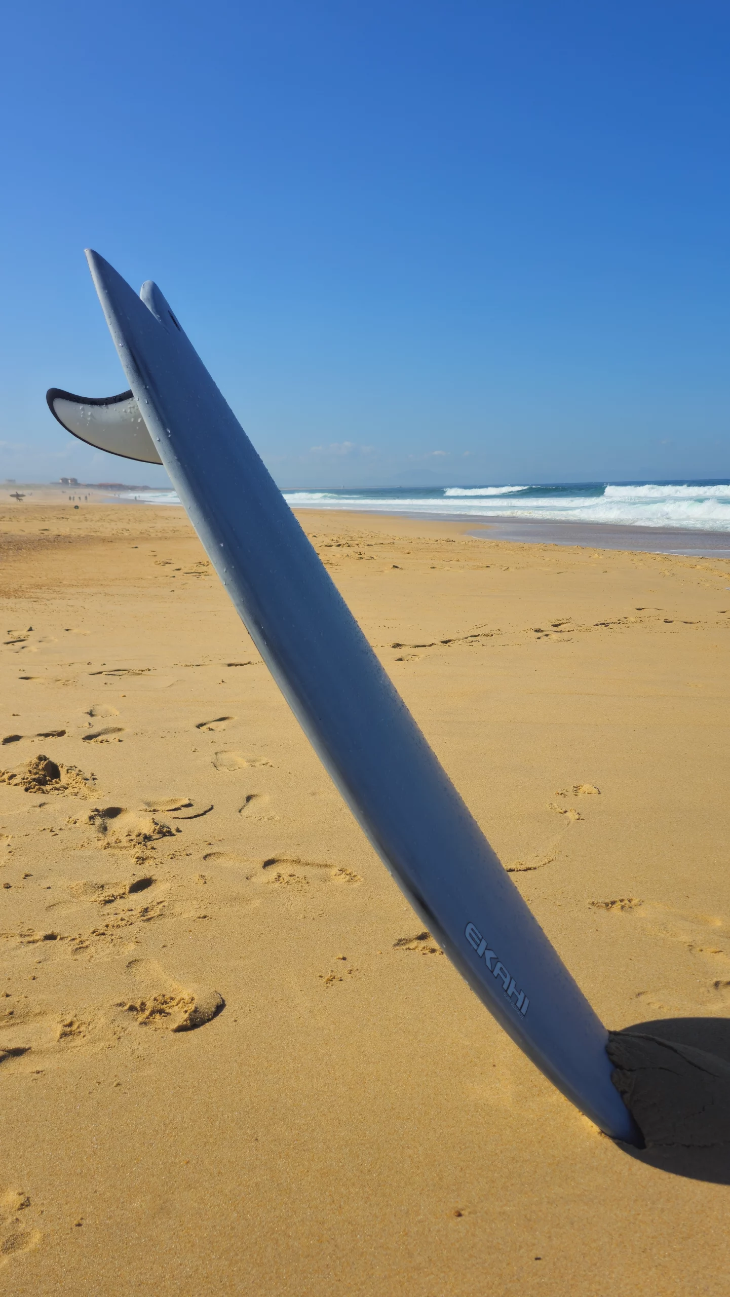 Rail view on the beach of the twin fish 22 pearl white carbon surfboard