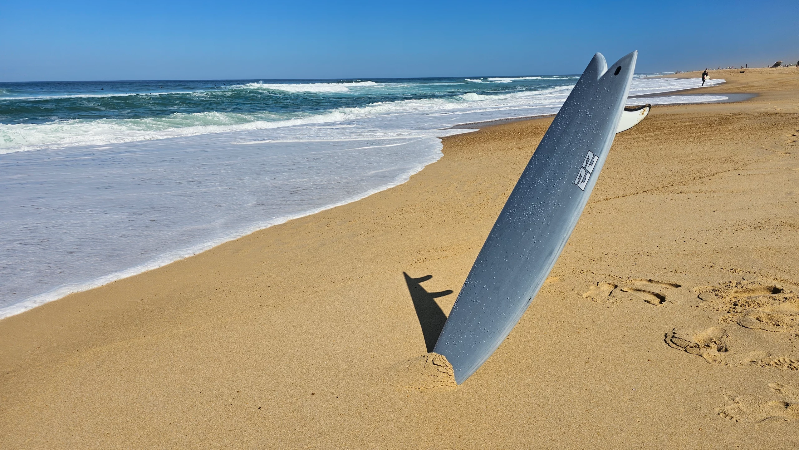 Top view on the beach of the vacuum bagging 22 pearl white carbon surfboard