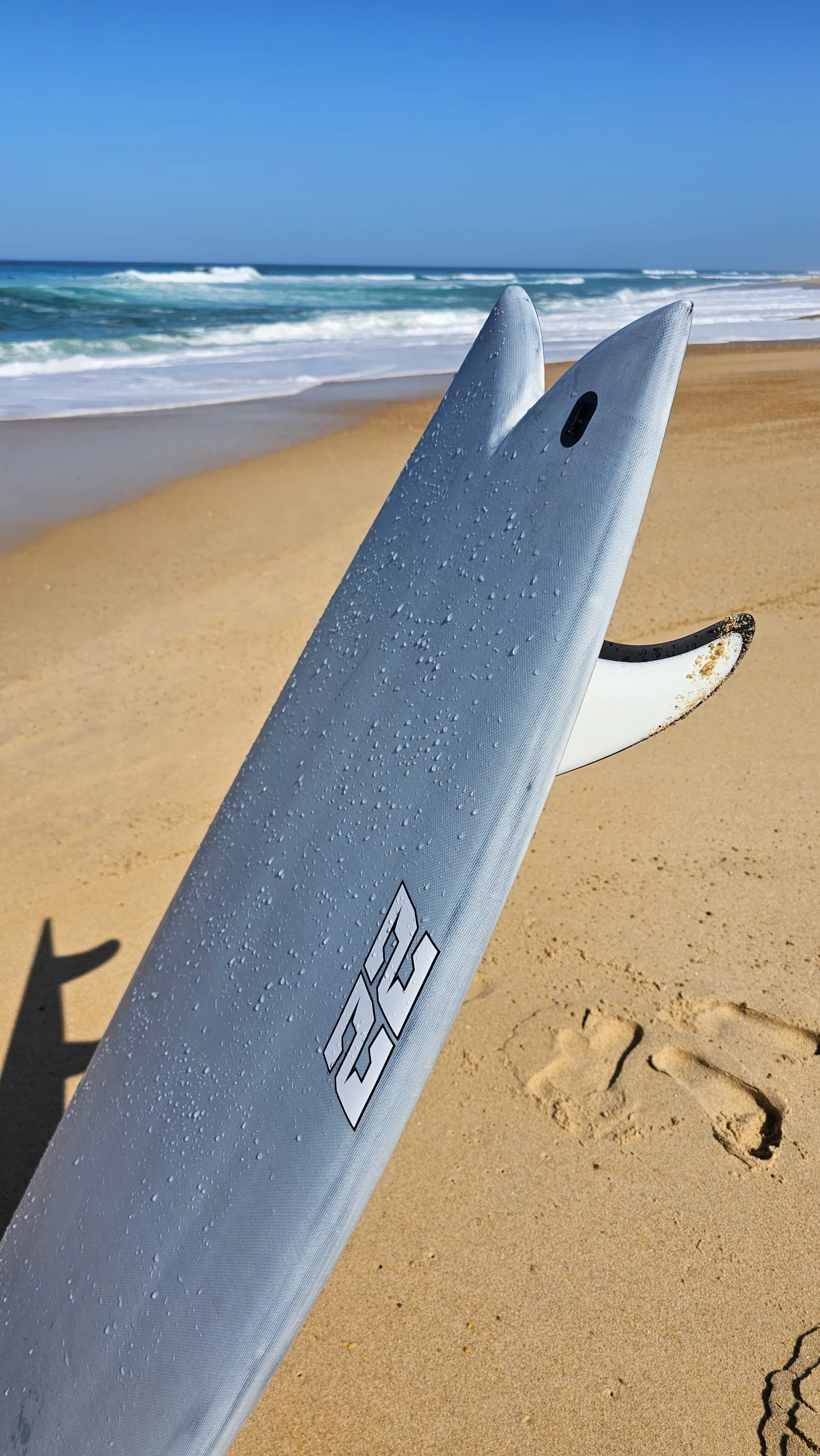Fish tail with the twin fins of the Ekahi pearl white 22 carbon surfboard