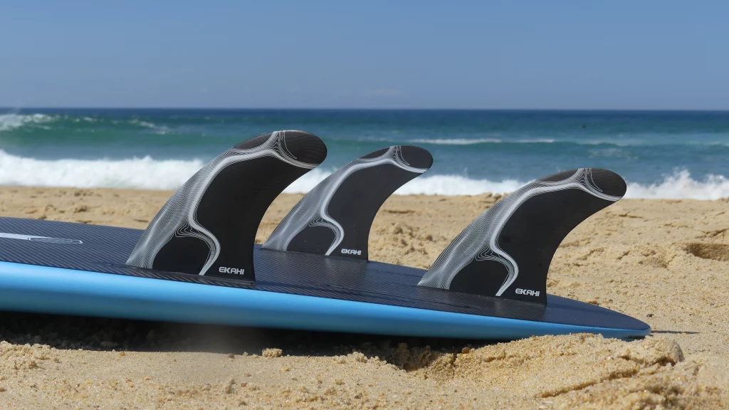 Close-up of fins on an Ekahi 53 carbon surfboard, blue deck
