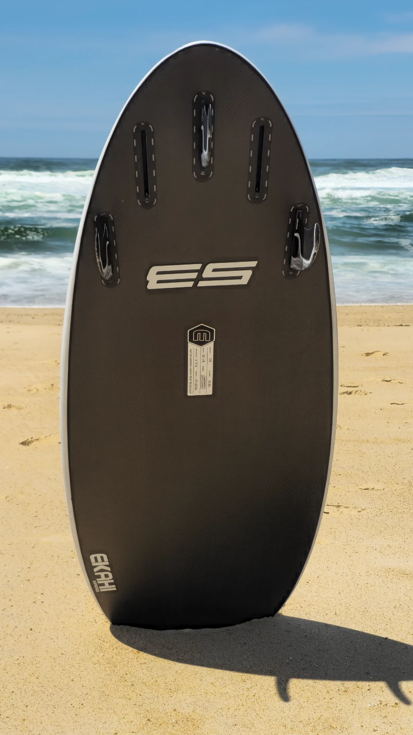 Bottom view of Ekahi white 53 hybrid five fins carbon surfboard on the beach.
