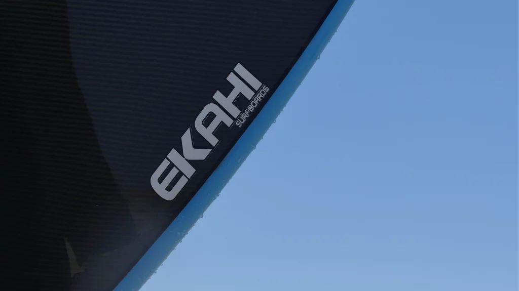 Close-up of the Ekahi logo on a blue Channels carbon surfboard