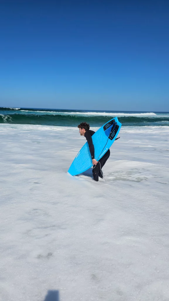 Ekahi Channels carbon surfboard, blue deck, lifestyle photo on the beach