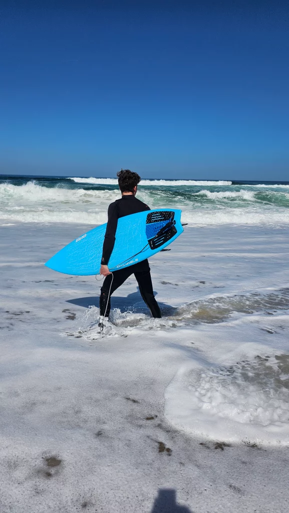 Ekahi Channels carbon surfboard, blue deck, lifestyle photo on the beach