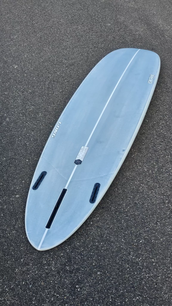 Ekahi Long surfboard on the pavement, bottom view with fins