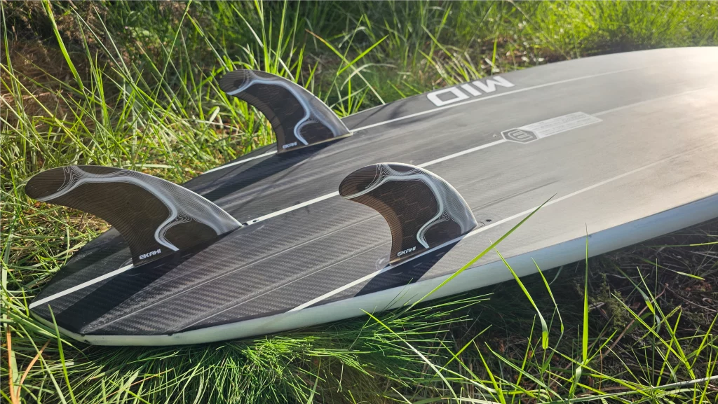 Close-up of fins on an Ekahi Mid Bois carbon surfboard, white deck