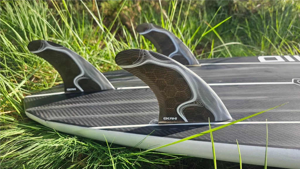 Close-up of fins on an Ekahi Mid Bois carbon surfboard, white deck