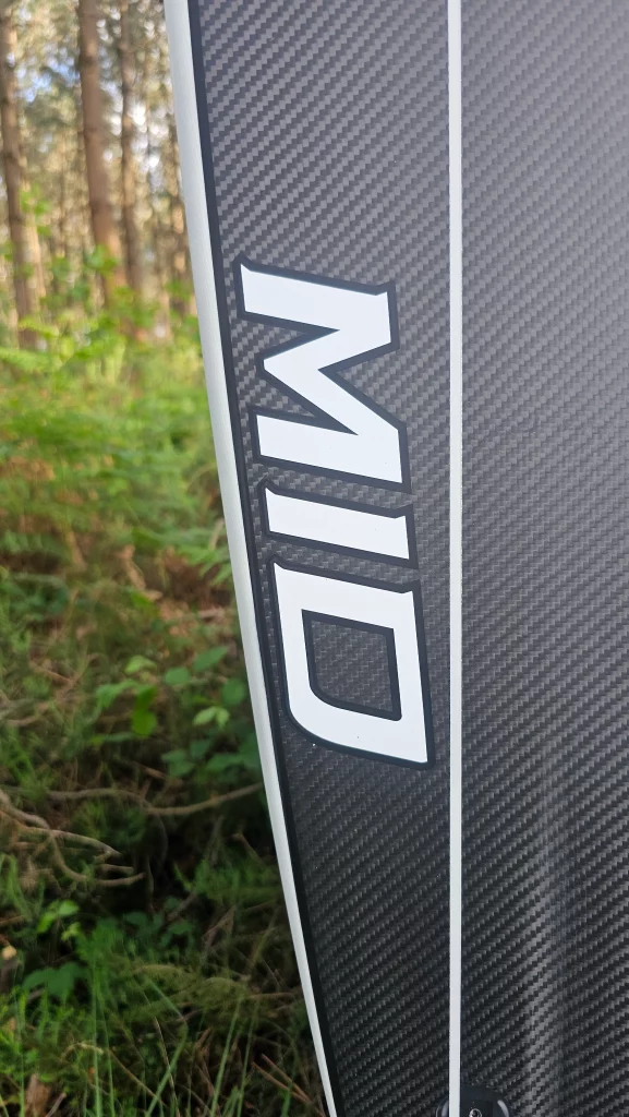 Close-up of the Ekahi logo on a white Mid Bois carbon surfboard