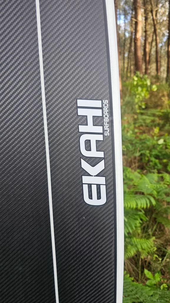 Close-up of the Ekahi logo on a white Mid Bois carbon surfboard