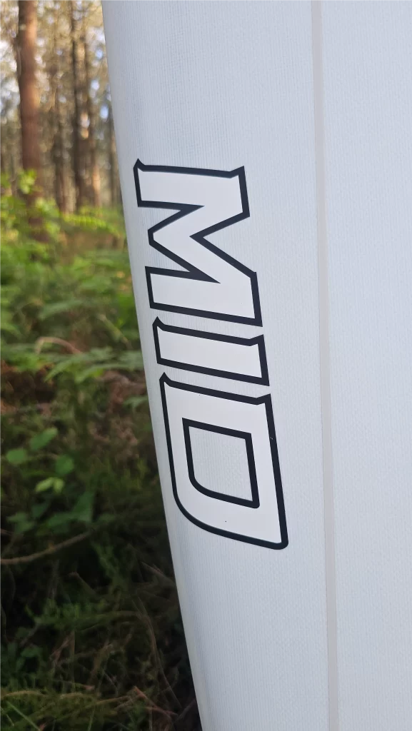 Close-up of the Ekahi logo on a white Mid Bois carbon surfboard