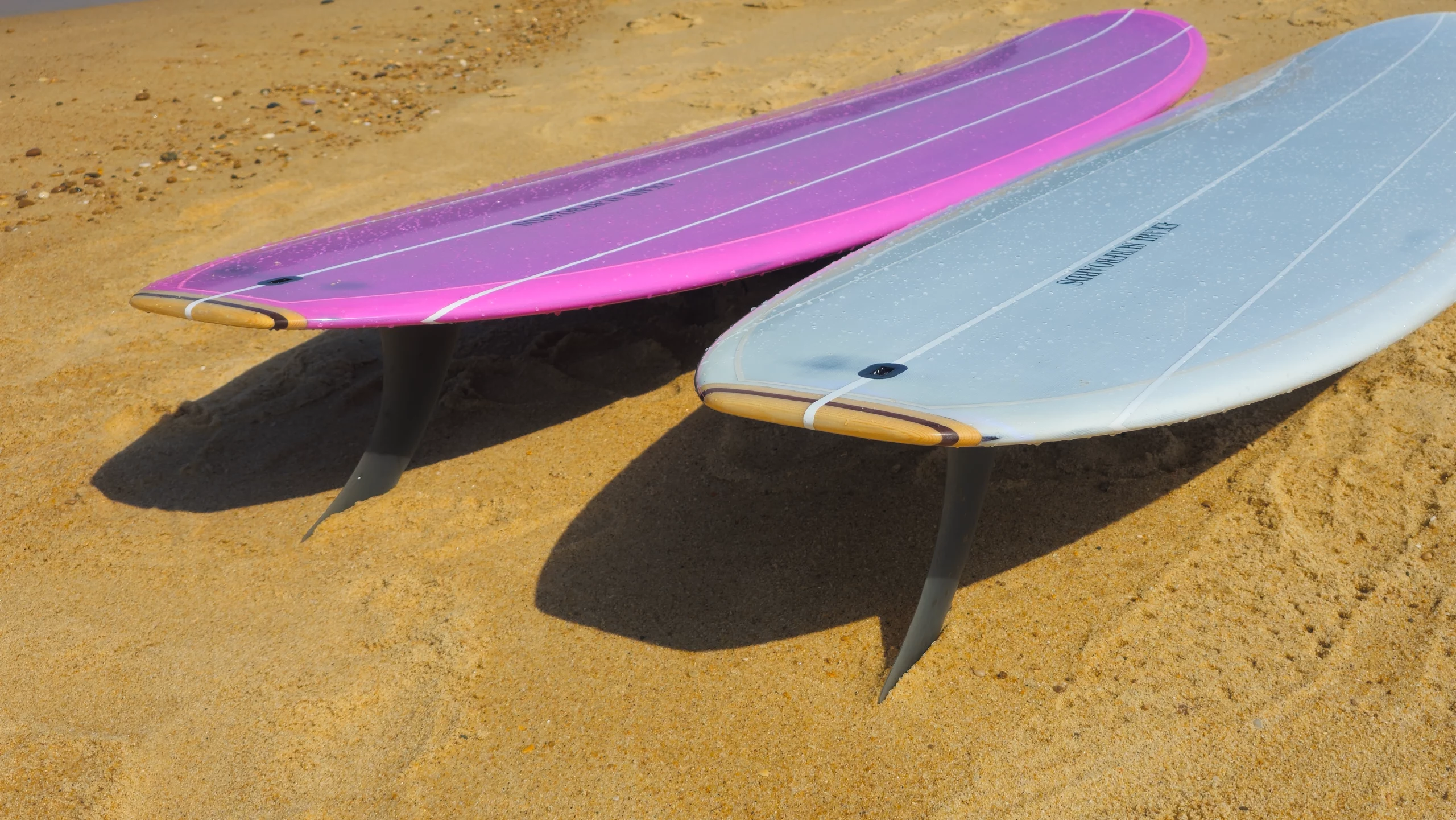 View of the wood tail of the Ekahi pearl white and pink Single longboard.