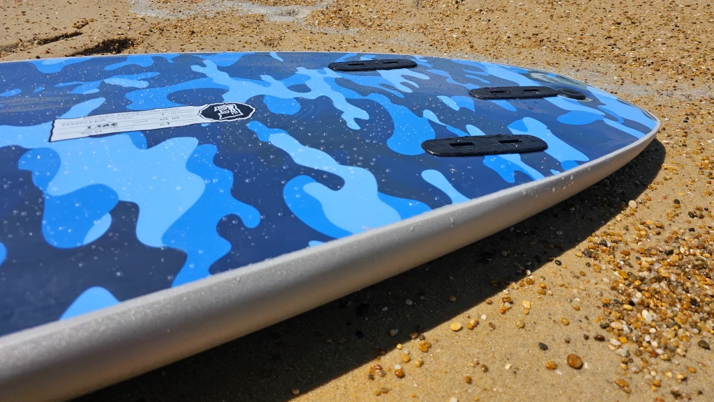 Close-up of the blue camo deck pattern on an Ekahi soft-top surfboard, rail view