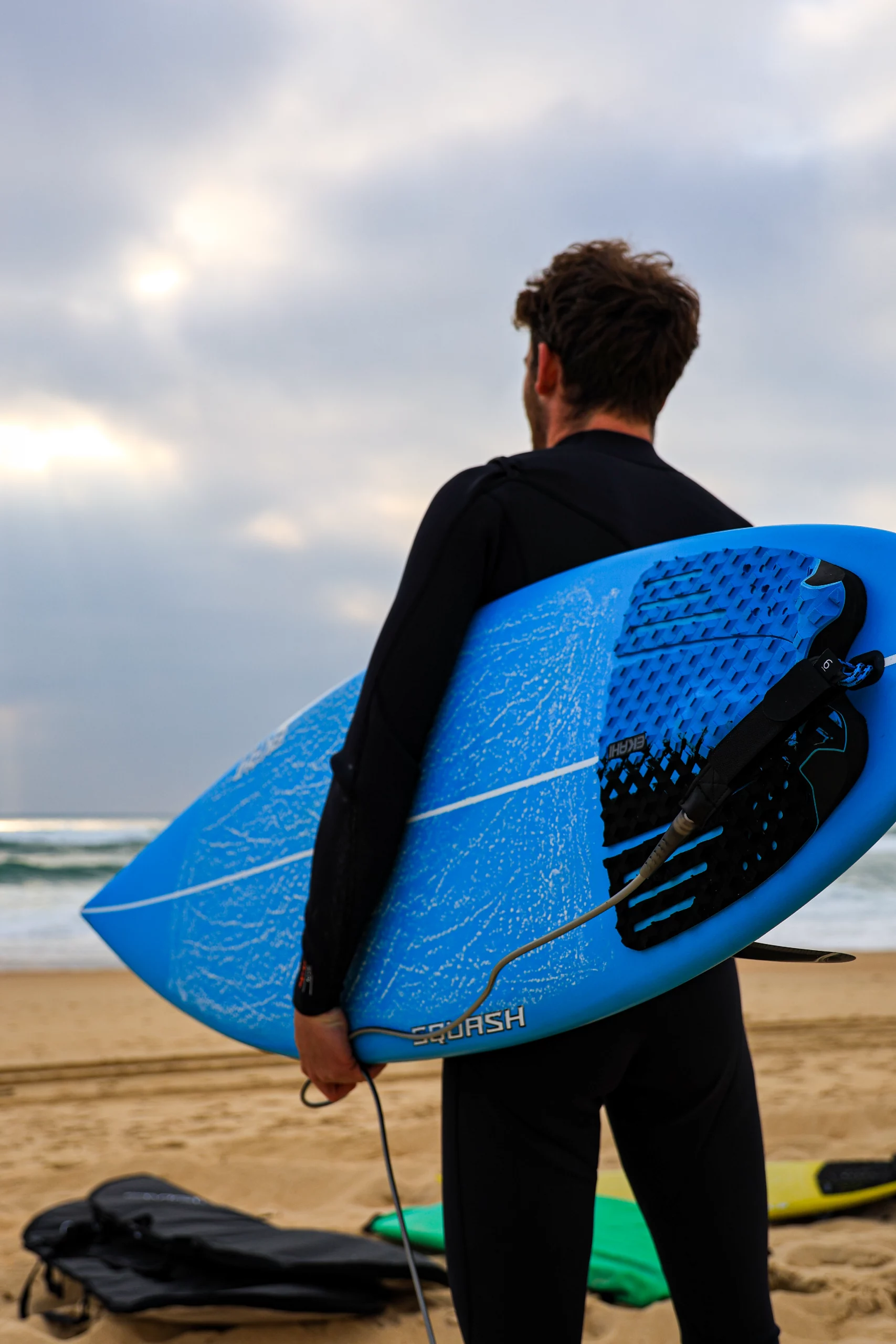 Top view of a Ekahi blue carbon Squash surfboard with a round bleu/black grip and a 6ft black/grey leash