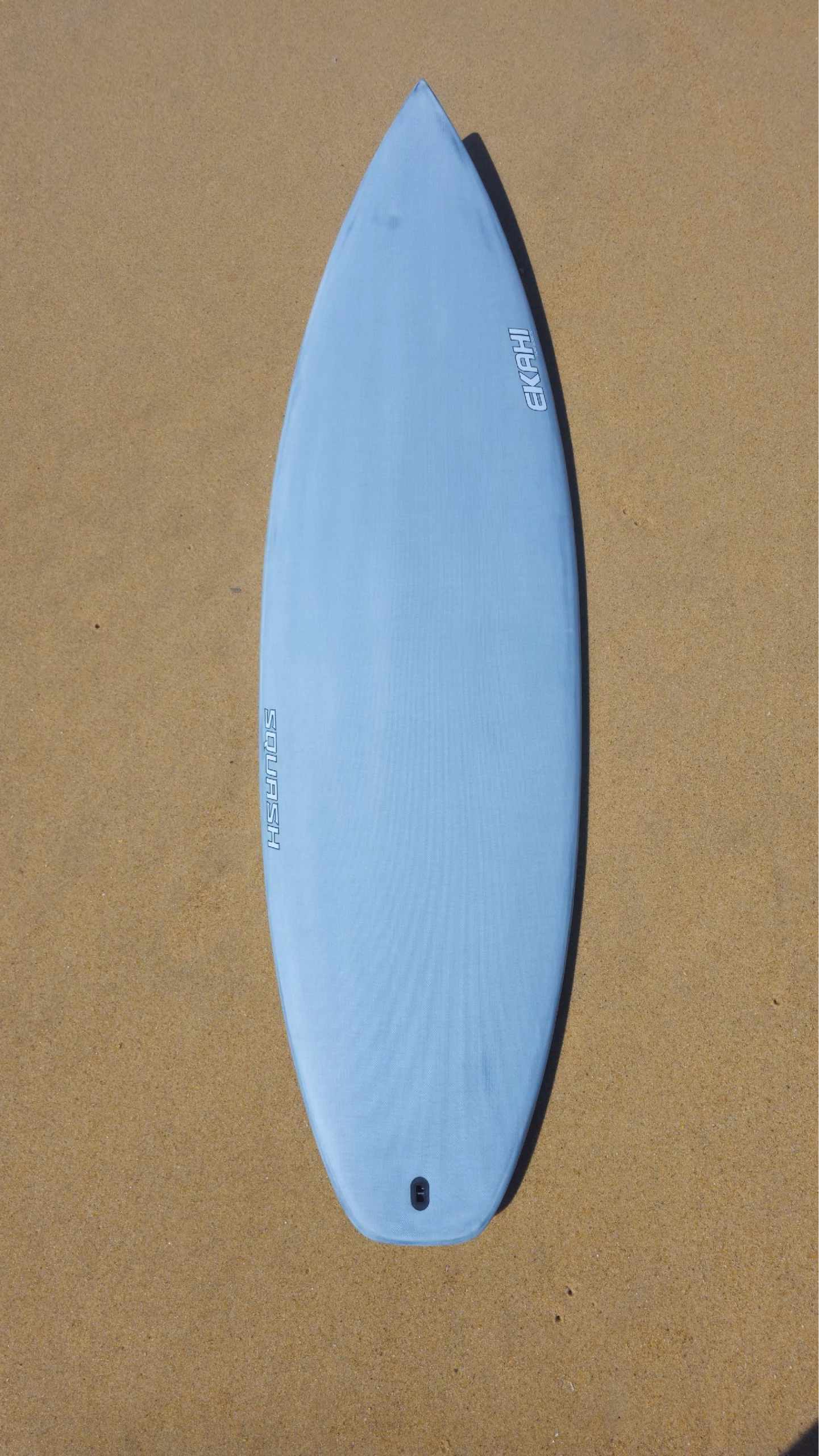 Top view of Ekahi white Squash performance carbon surfboard on the beach.