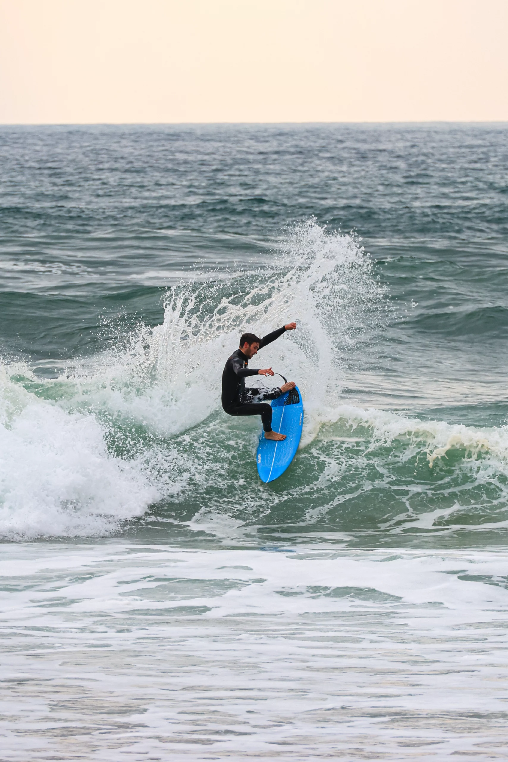 Surfer making a roller with the blue 5'8 Squash in carbon technology