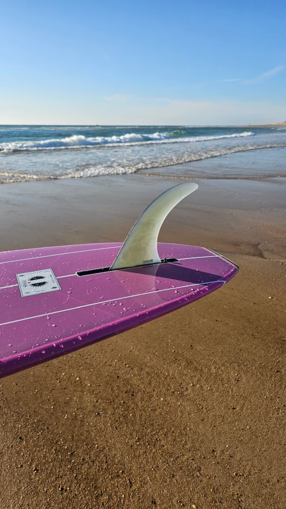 View of the single fin on the pink classic longboard at the beach.