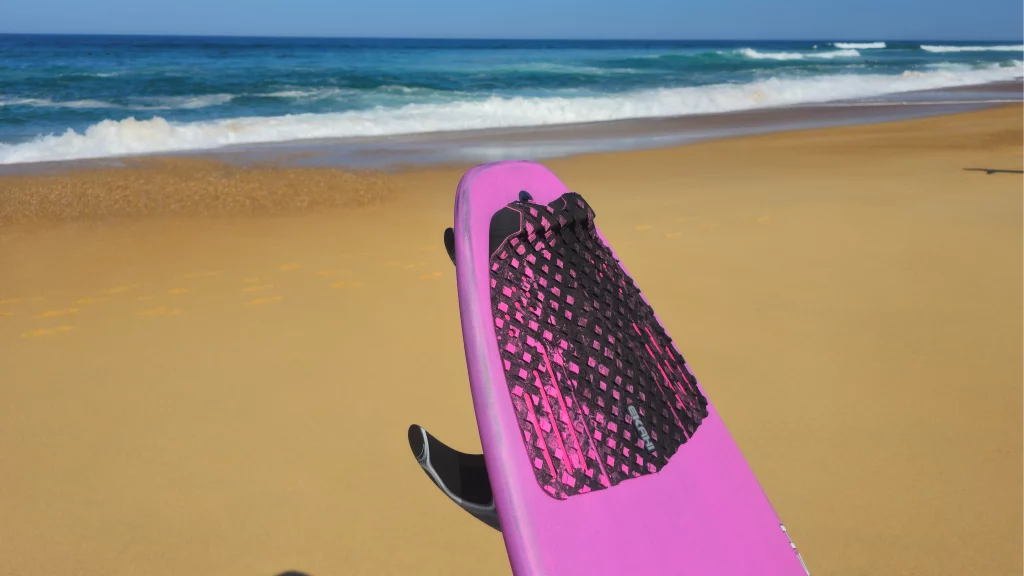Ekahi Squash Pad carbon surfboard, pink deck, lifestyle photo on the beach