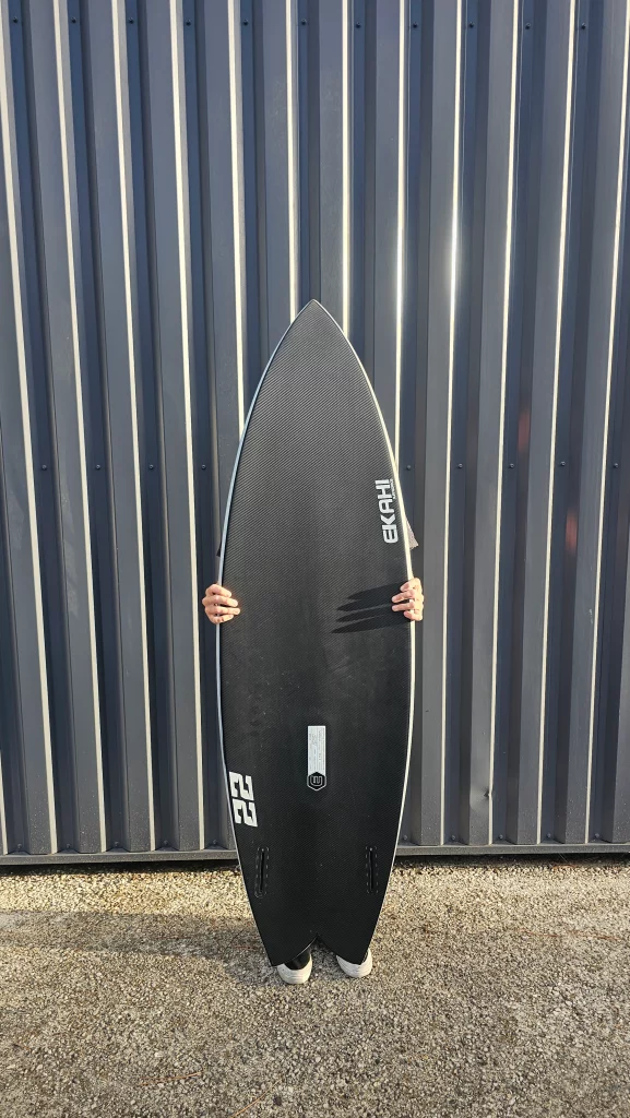 Ekahi 22 carbon surfboard, white deck, bottom view, held by hand for scale