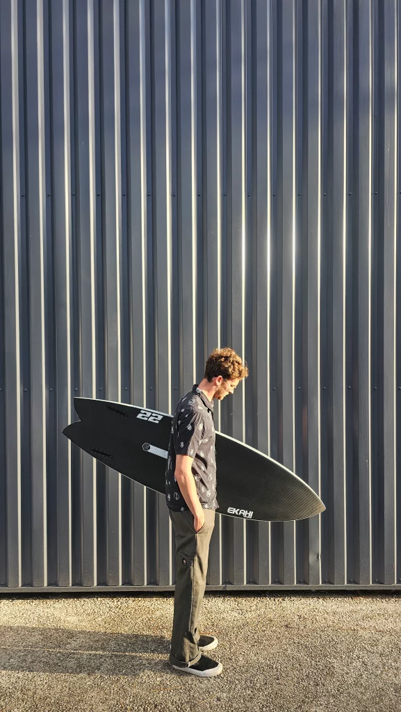 Ekahi 22 carbon surfboard, white deck, bottom view, held by hand for scale