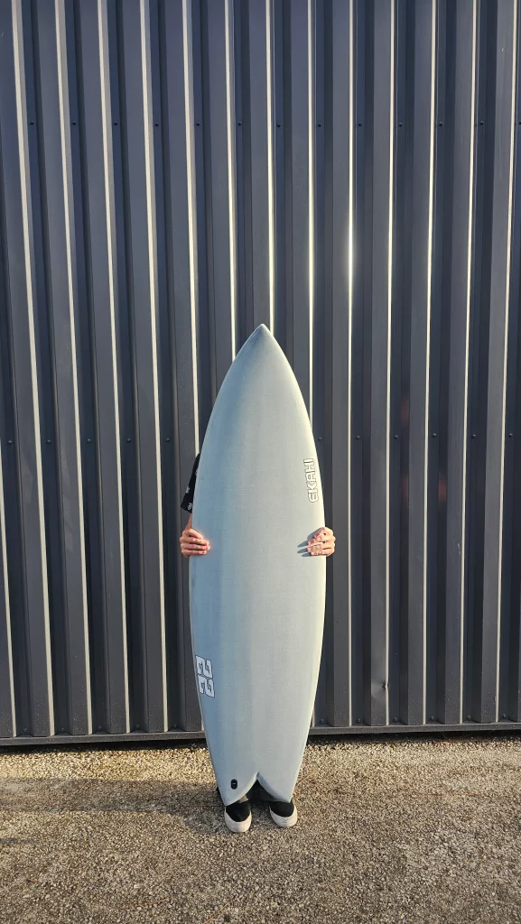 Ekahi 22 carbon surfboard, white deck, top deck view, held by hand for scale