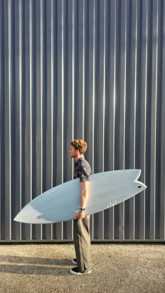 Ekahi 22 carbon surfboard, white deck, top deck view, held by hand for scale