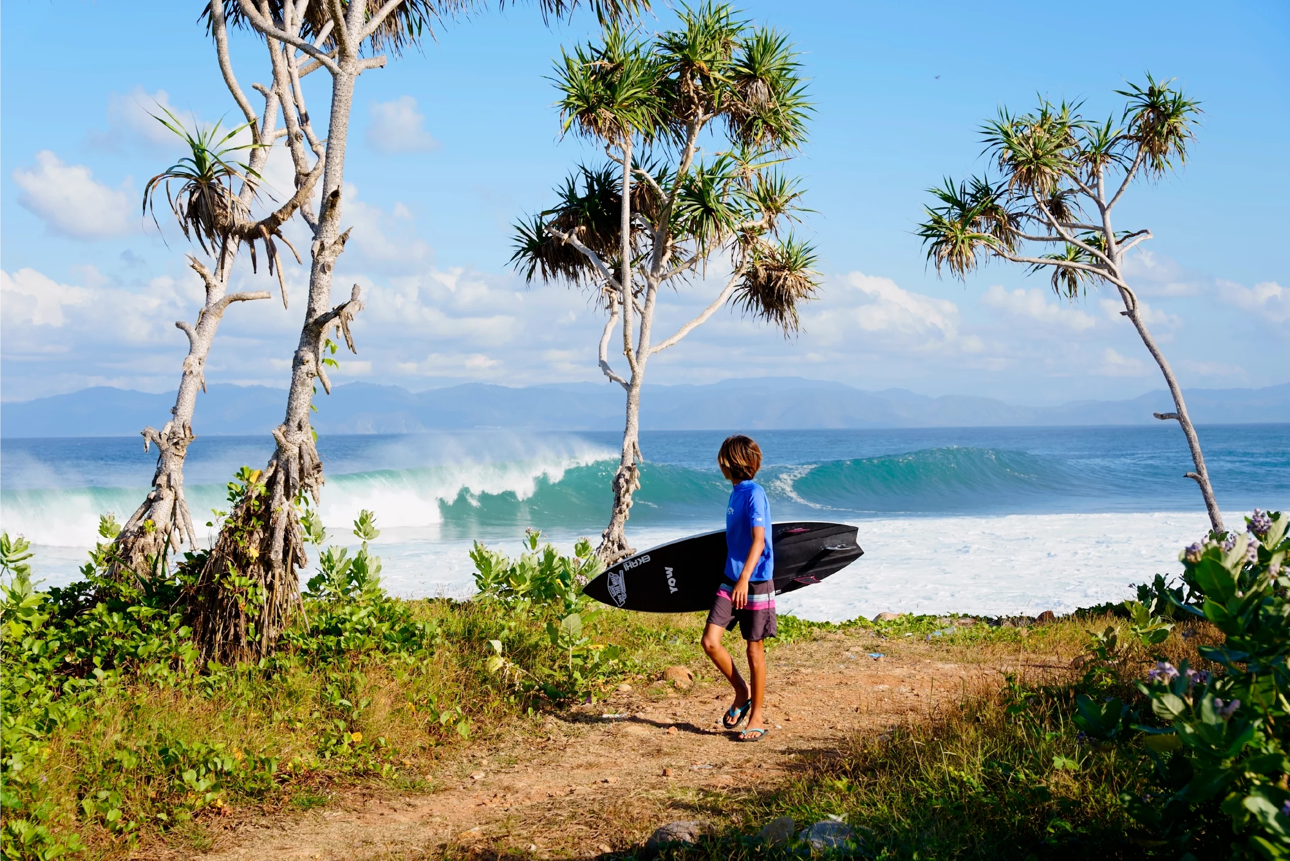 View of a guy coming back with a white 5'0 Channels Ekahi carbon surfboard.