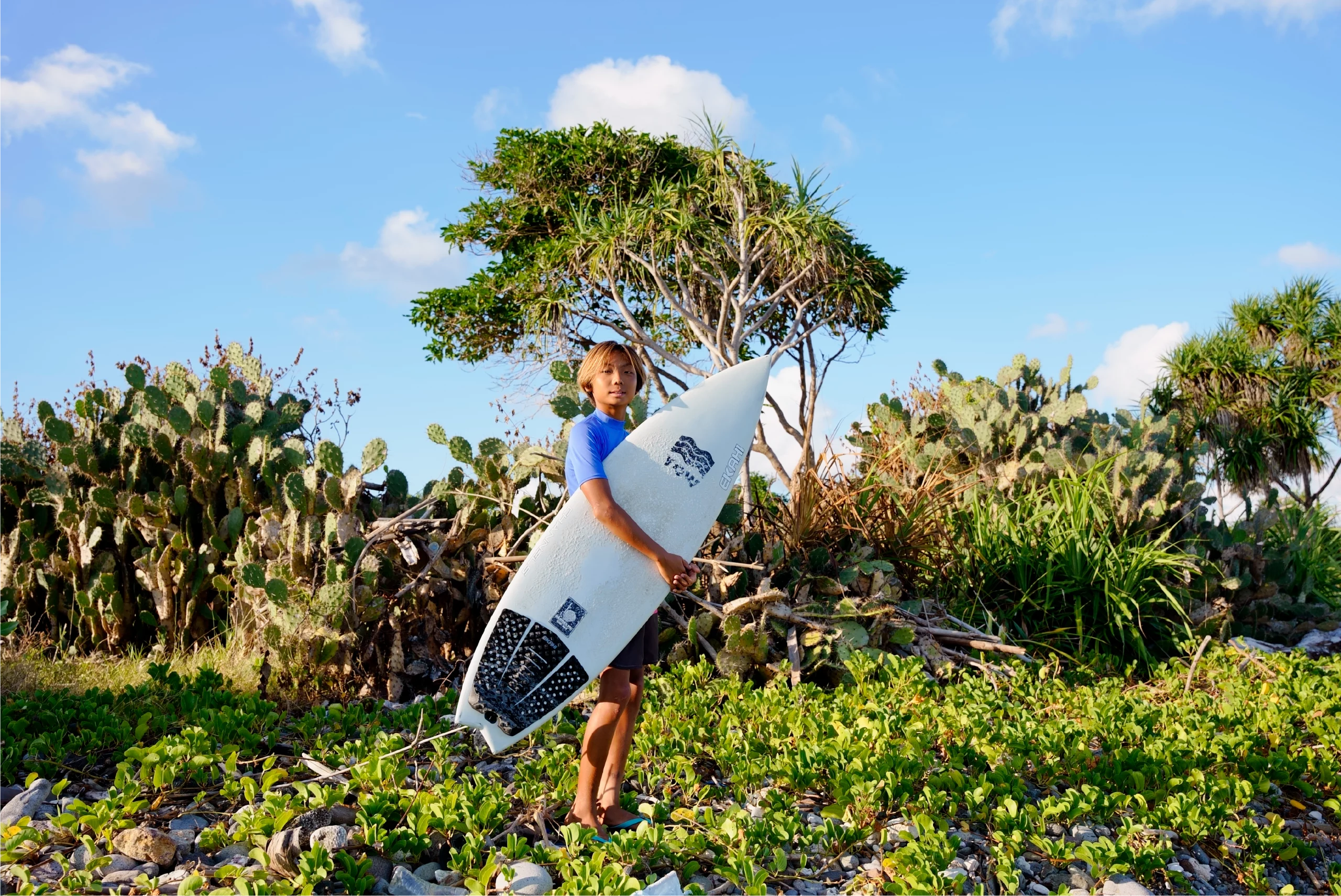 Top view of a guy carrying a white 5'0 channels and a grom marble traction pad.