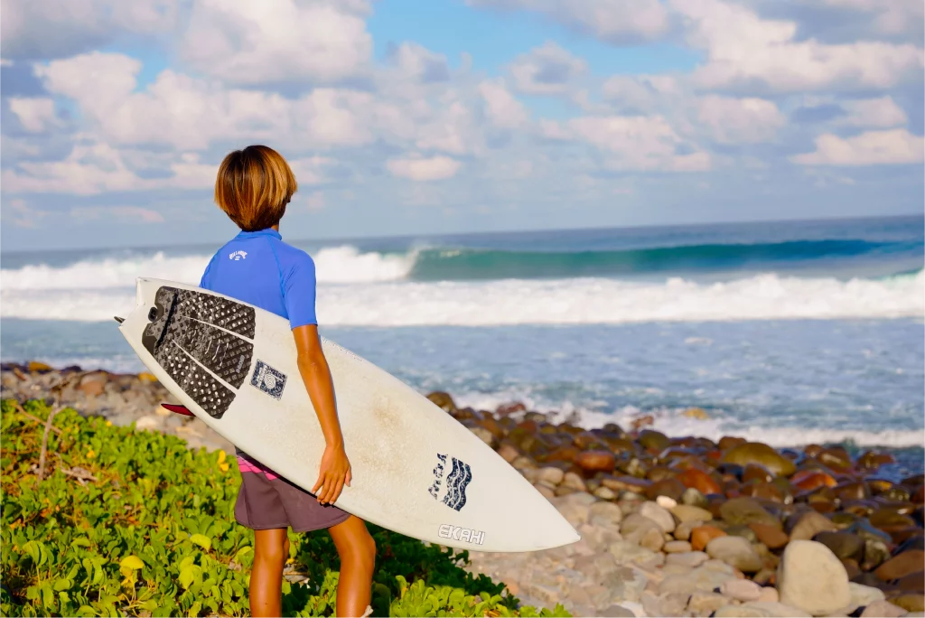 Guy looking at the wave with a top view of a white channels and a grom marble traction pad