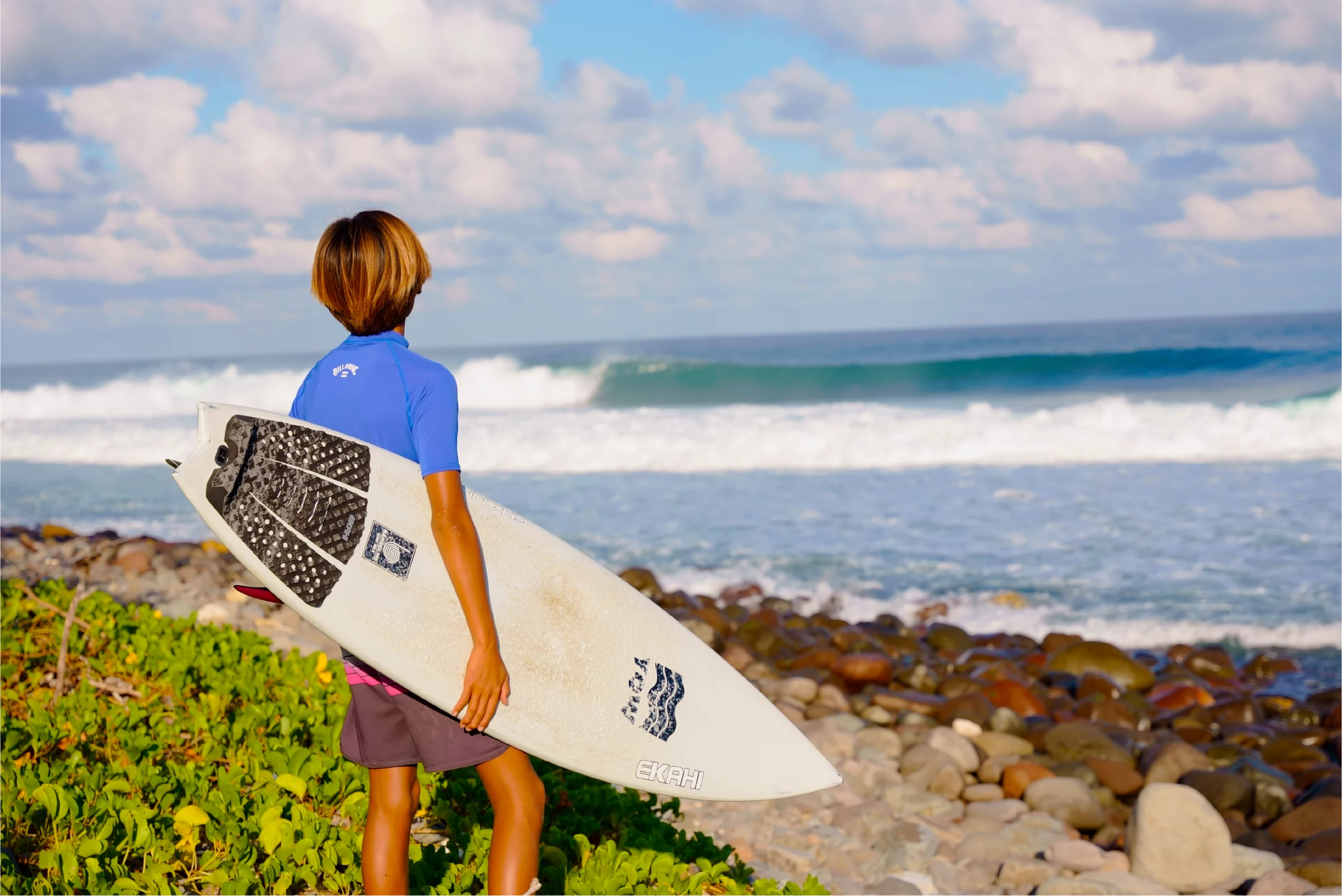 Guy looking at the wave with a top view of a white channels and a grom marble traction pad