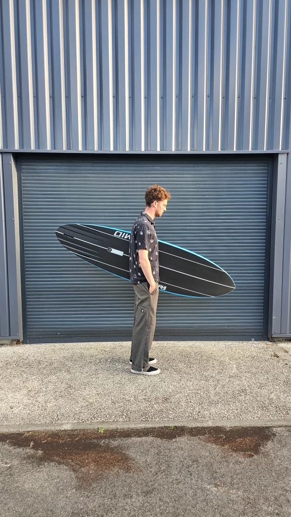 Ekahi Mid carbon surfboard, blue deck, bottom view, held by hand for scale