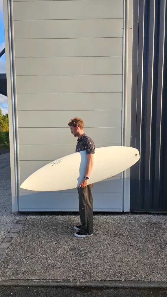 Ekahi Squash carbon surfboard, white deck, top deck view, held by hand for scale