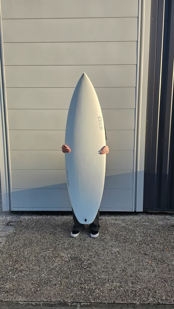 Ekahi Squash carbon surfboard, white deck, top deck view, held by hand for scale