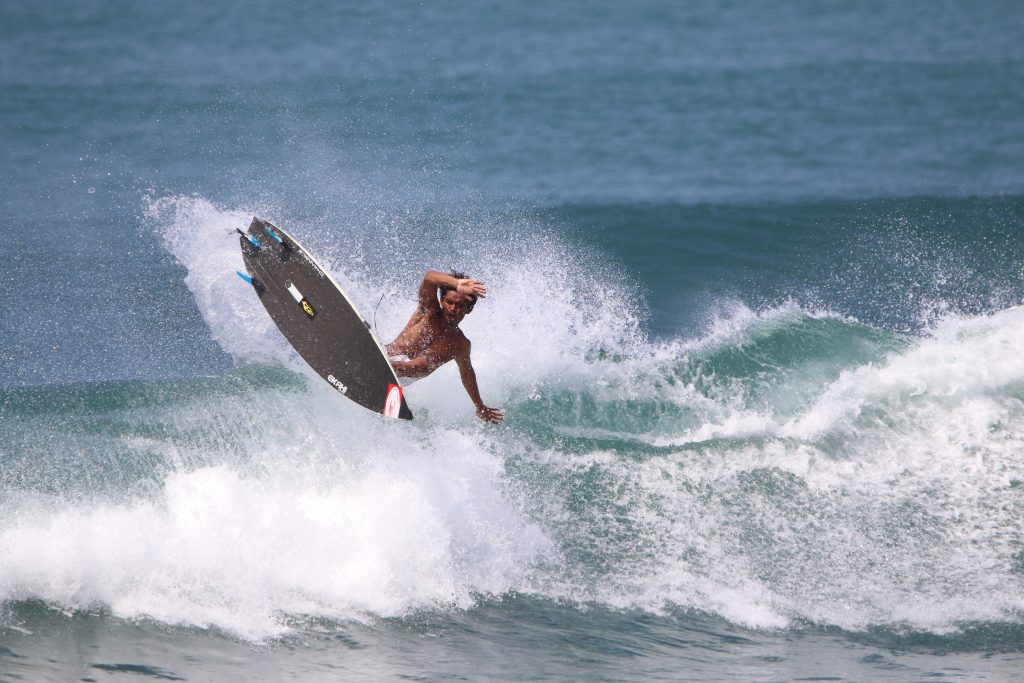 Surfer carving on an EKAHI carbon surfboard